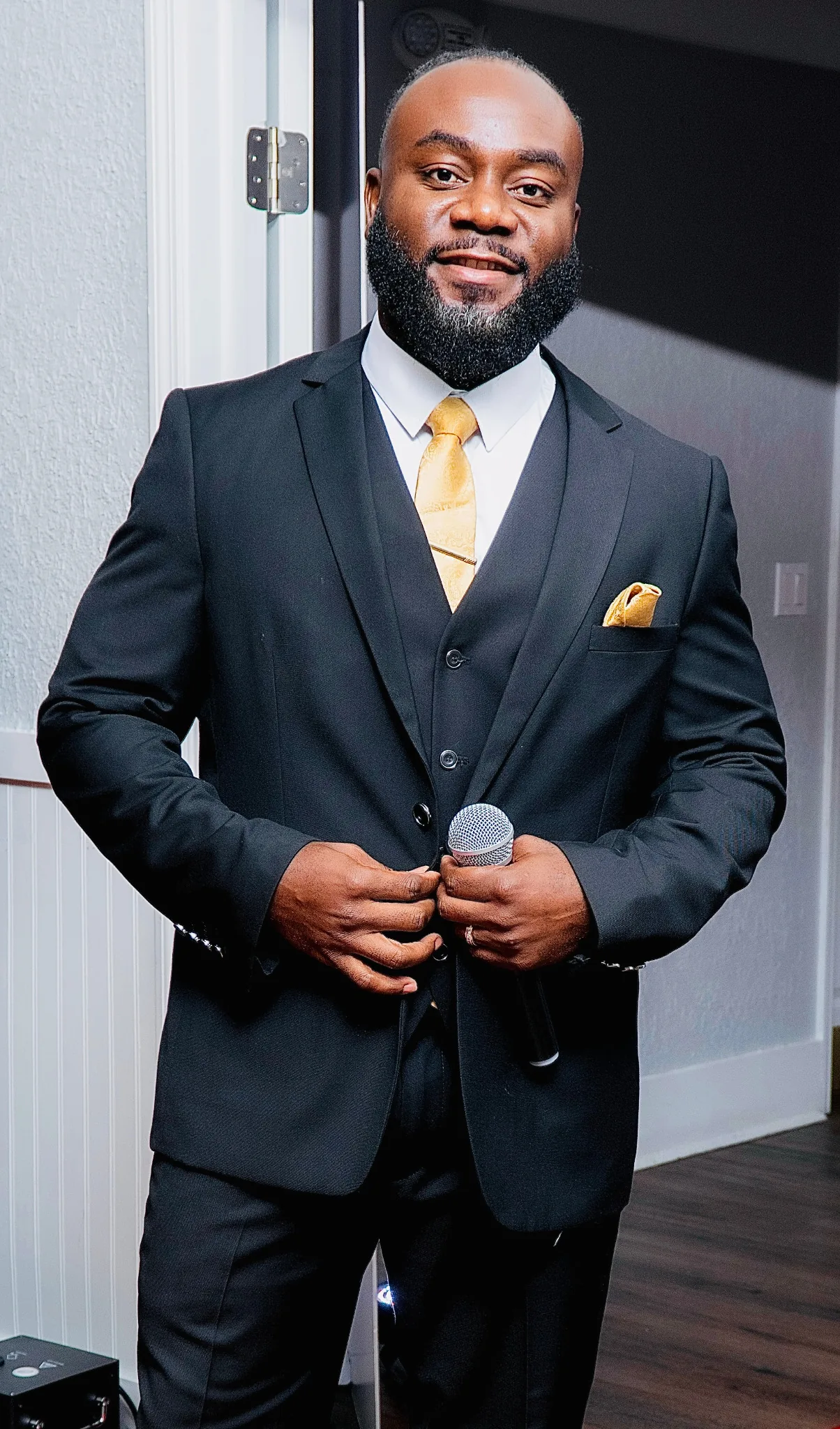 DJ Haish in a black suit holding a microphone